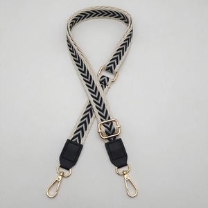 Detail of adjustable woven strap with beige and black chevron pattern and gold metal hooks