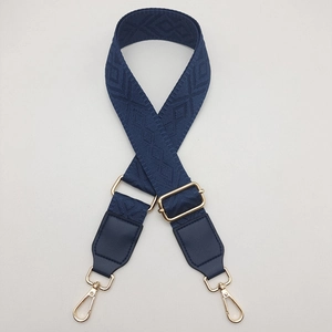 Detail of navy blue wide jacquard bag strap with golden metal lobster clasps and adjustments