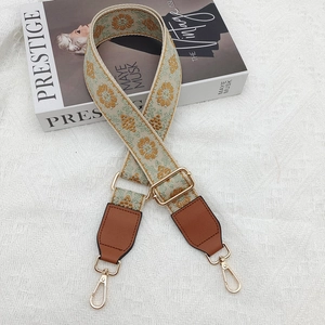 Detail of wide embroidered purse strap with floral pattern and golden metal swivel hooks
