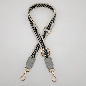 Adjustable black and white chevron pattern woven strap with grey leather ends and gold buckles