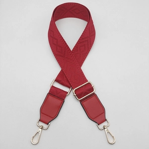 Detail of red jacquard replacement bag strap with diamond texture and gold metal hooks