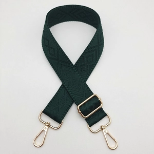 Macro shot of dark green diamond weave shoulder strap with gold metal buckle