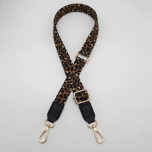 Detail view of leopard print bag strap with golden metal hardware and black leather ends
