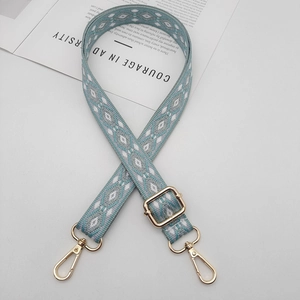 Detail of bohemian woven wide bag strap with teal geometric patterns and gold lobster clasps
