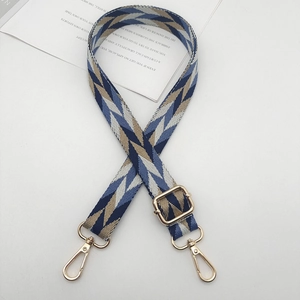 Adjustable wide woven bag strap with blue and beige geometric pattern and gold hardware
