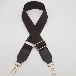 Detail of dark brown woven bag strap with geometric patterns and golden metal buckles