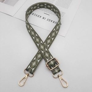 Detail of adjustable woven shoulder strap with green geometric patterns and gold clips