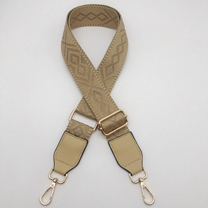 Close-up of geometric jacquard bag strap with leather ends and golden metal buckles
