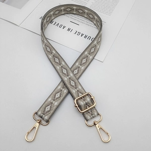 Close-up of woven adjustable shoulder strap with grey geometric pattern and gold hardware
