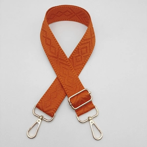 Close-up of orange wide shoulder strap with woven diamond pattern and silver hardware