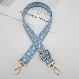 Detail of adjustable blue woven bag strap with ethnic geometric patterns and gold metal clips