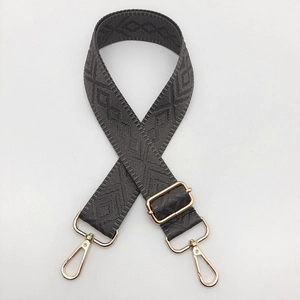 Close-up of adjustable gray guitar-style bag strap with geometric diamond weave and gold hardware