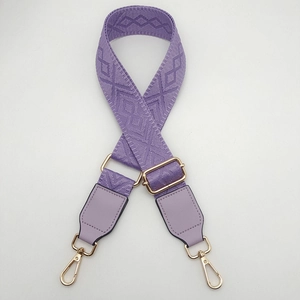 Detail of purple geometric jacquard woven strap with gold metal hooks and leather tabs