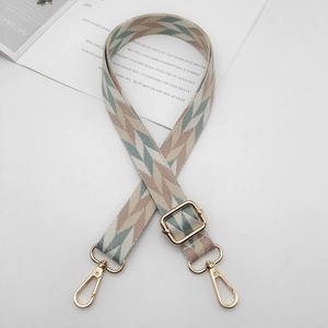 Detail of adjustable wide woven bag strap with geometric patterns and gold metal buckles