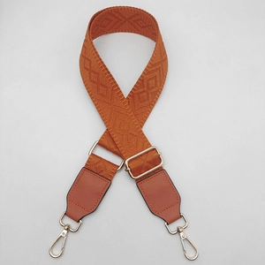Detail of adjustable caramel orange wide strap with jacquard weave and gold lobster clips