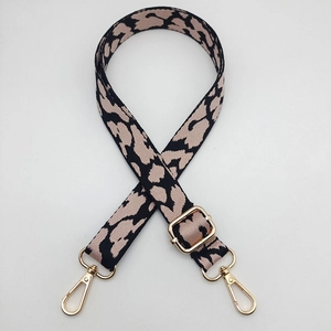 Detailed view of leopard print woven bag strap with golden metal lobster clasps
