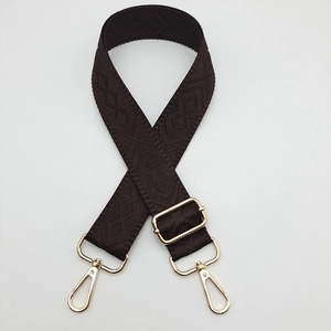 Detail of adjustable dark brown crossbody strap with golden hardware and rhombic pattern
