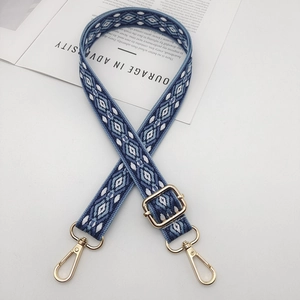 Adjustable geometric blue woven shoulder strap with gold metal hooks on white background