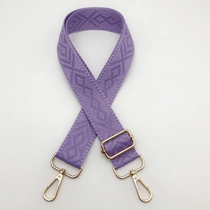 Close-up of purple diamond patterned woven shoulder strap with gold metal buckles