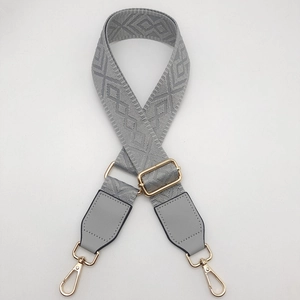 Detail of adjustable wide shoulder strap with light gray jacquard pattern and gold hardware