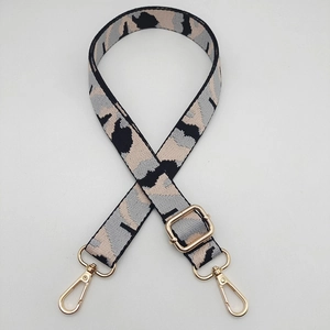 Close-up of camo jacquard wide bag strap with light gold metal swivel hooks and slider