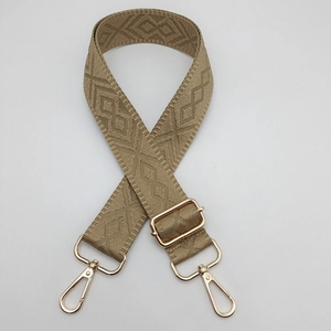 Detail of adjustable khaki woven bag strap with geometric diamond pattern and gold hardware