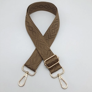 Detail view of brown diamond pattern crossbody bag strap with gold metal lobster clasps
