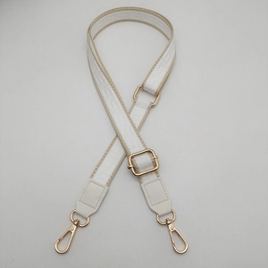 Macro shot of white meander pattern webbing strap with luxury gold metal hardware