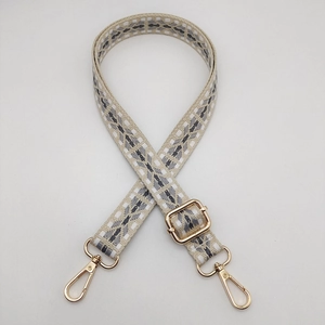 Detail of adjustable nylon backpack strap with geometric patterns and gold metal hooks