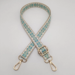 Detail of adjustable nylon bag strap with ethnic geometric embroidery and gold hooks