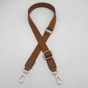 Detail of brown geometric pattern strap with adjustable gold buckles and leather ends