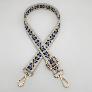 Detail of adjustable nylon bag strap with geometric jacquard pattern and gold metal hooks