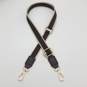 Detail of adjustable geometric jacquard shoulder strap with brown leather and gold buckles