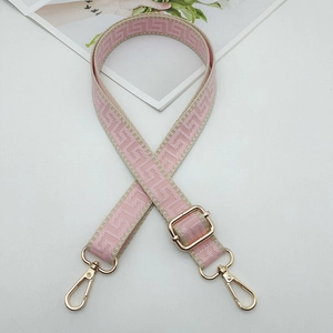 Detail of adjustable pink and beige geometric woven bag strap with gold lobster clasps