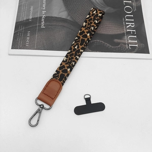 Detail of leopard print phone wrist strap with dark gray metal hook and black tether tab