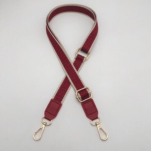 Detail of adjustable wide shoulder strap with red geometric Greek key pattern and gold buckles