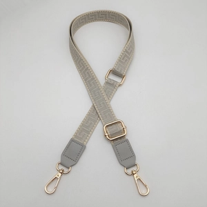 Detailed view of gray maze pattern crossbody bag strap with leather and gold buckle