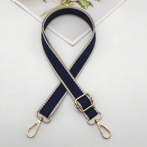 Detail of blue adjustable bag strap with white Greek fret pattern and gold metal hooks