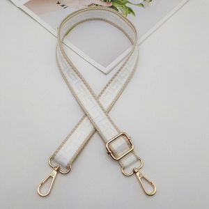 Detail of adjustable woven bag strap with beige Greek key pattern and gold metal hardware