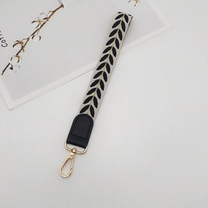Close-up of leaf embroidery strap with black leather detail and golden lobster clasp