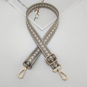 Detail of adjustable woven nylon strap with white chevron patterns and gold metal clasps