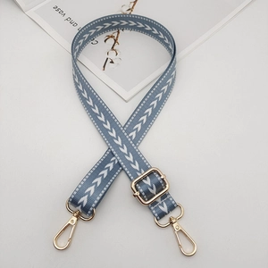 Detail of adjustable blue and white woven pattern bag strap with gold metal hardware