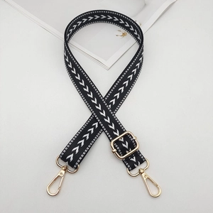 Detail of adjustable black and white nylon bag strap with gold lobster clasps and hardware