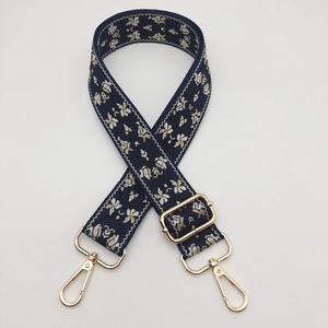 Detail of adjustable navy jacquard strap with floral embroidery and golden metal hooks
