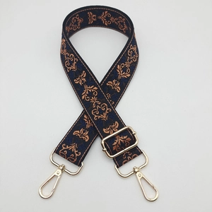 Detail of adjustable blue jacquard strap with vintage patterns and gold metal buckles
