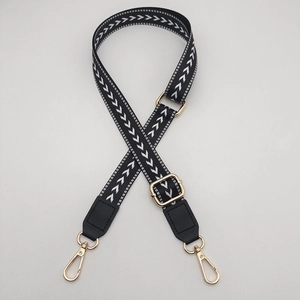 Detail of adjustable black woven strap with white arrow pattern and gold metal hardware