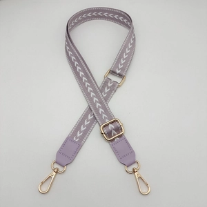 Detail view of light purple woven shoulder strap with gold metal hardware and texture