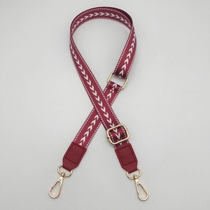 Macro shot of 2.5cm adjustable burgundy bag strap with white arrow pattern and gold clips