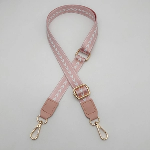 Adjustable light pink crossbody bag strap with white arrow pattern and gold metal hooks