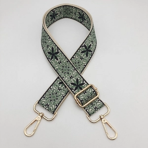 Dettaglio della tracolla intrecciata stile etnico verde e bianco con clip in lega dorata